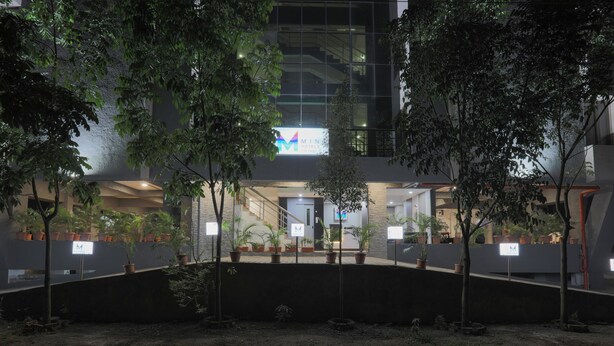 A modern building with a sign reading "MINA HOTEL" and a well-lit entrance. - Hotel Mint Highstreet (Pune)