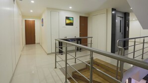 A clean, modern hotel hallway with a staircase, wooden doors, and a metal railing. - Hotel Mint Highstreet (Pune)