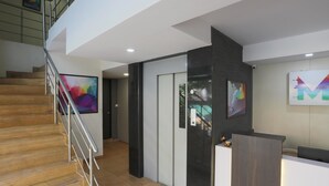 A modern reception area with a wooden staircase, a reception desk, and abstract art on the walls. - Hotel Mint Highstreet (Pune)