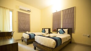 A hotel room with two beds, a wooden dresser, and an air conditioning unit. - Hotel Mint Highstreet (Pune)