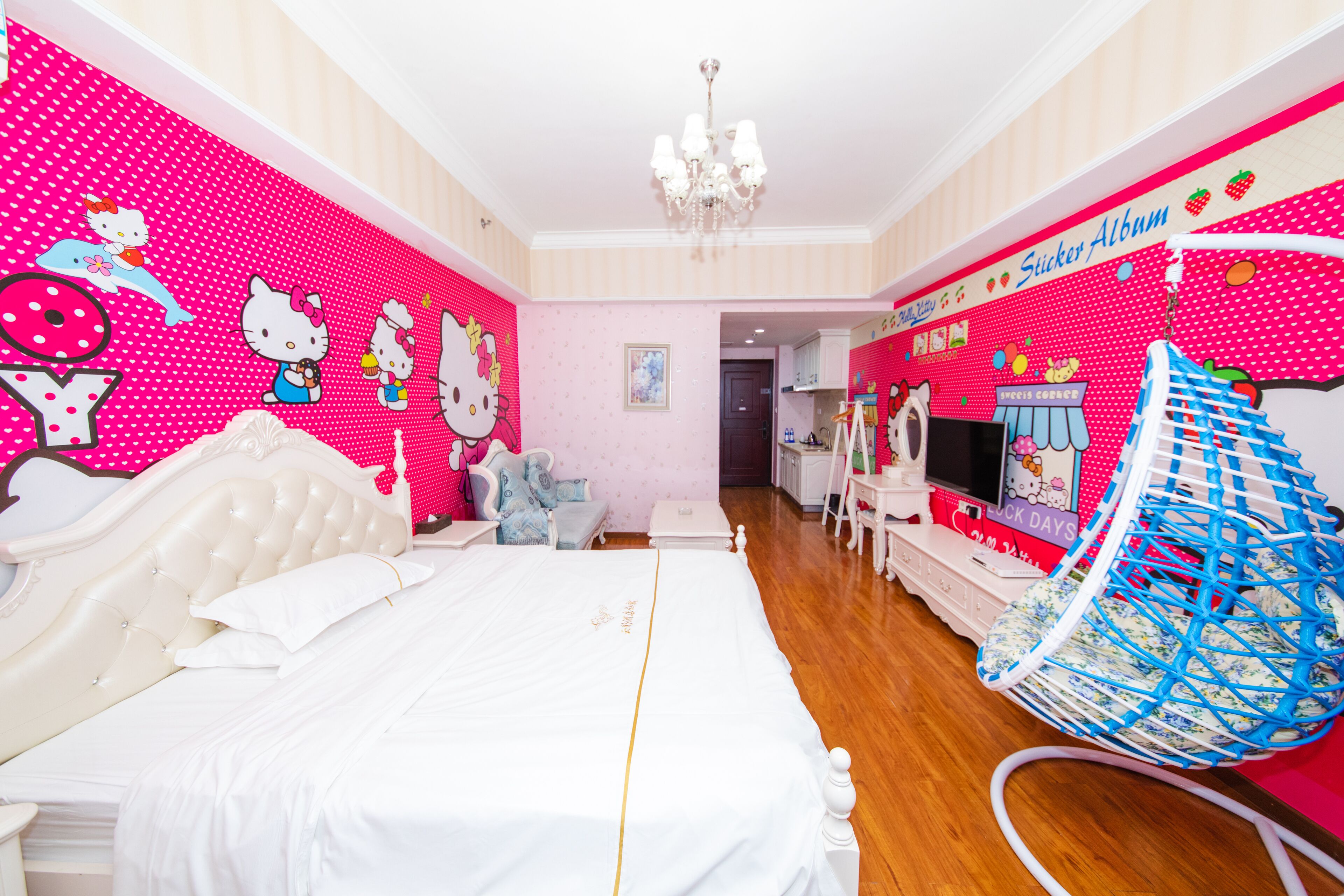 A bedroom with a large bed, a hanging chair, and a wall decorated with Hello Kitty and other characters.