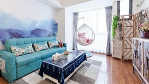 A living room with a blue sofa, a hanging chair, and a decorative wall. - Lavender Apartment -Wanda Branch (Guangzhou)