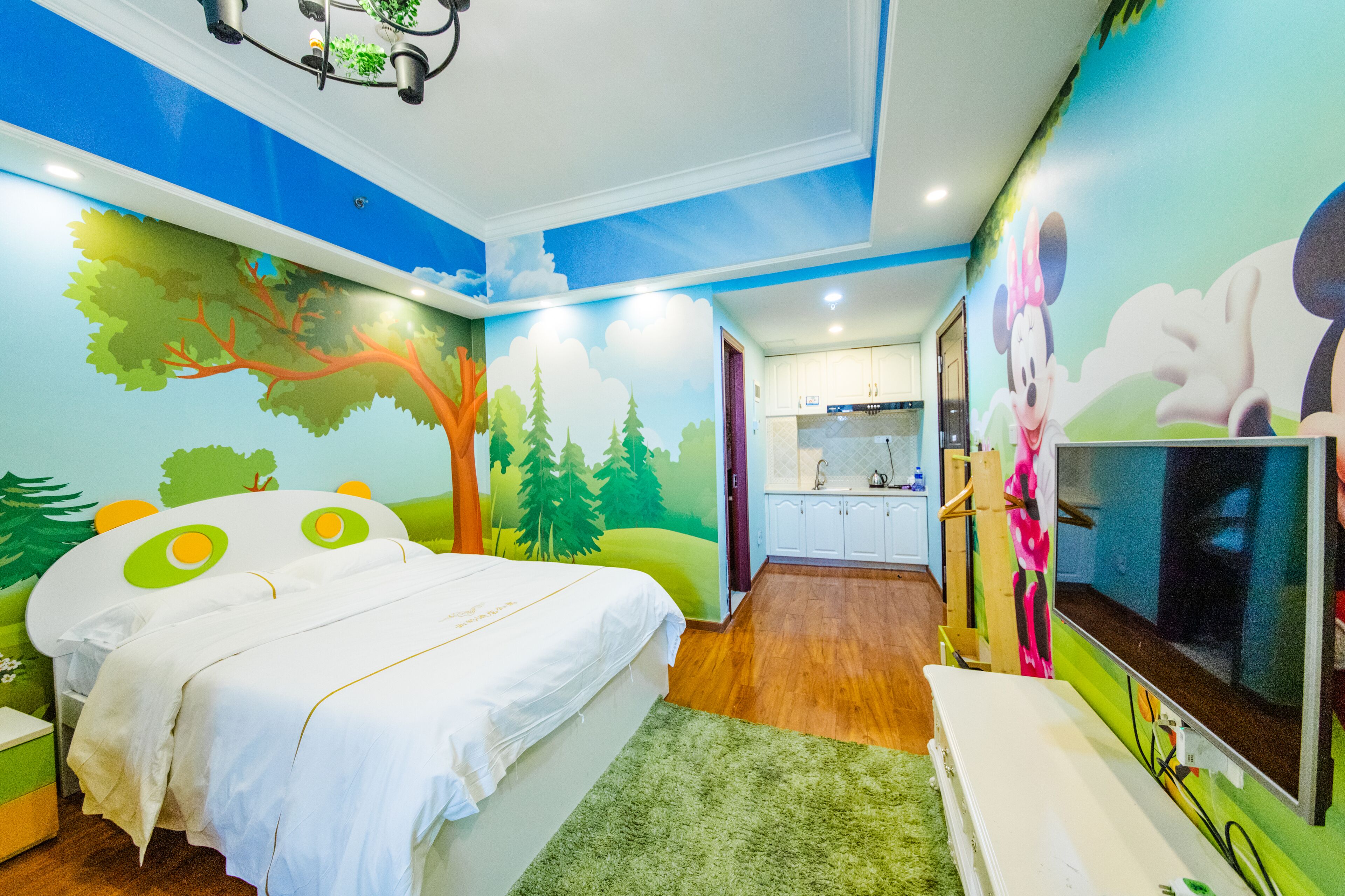 A bedroom with a bed, a TV, and a mural of a cartoon character.