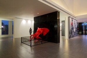 Een modern interieur met een grote zwarte muur, een rode sculptuur en een persoon die bij een whiteboard staat.