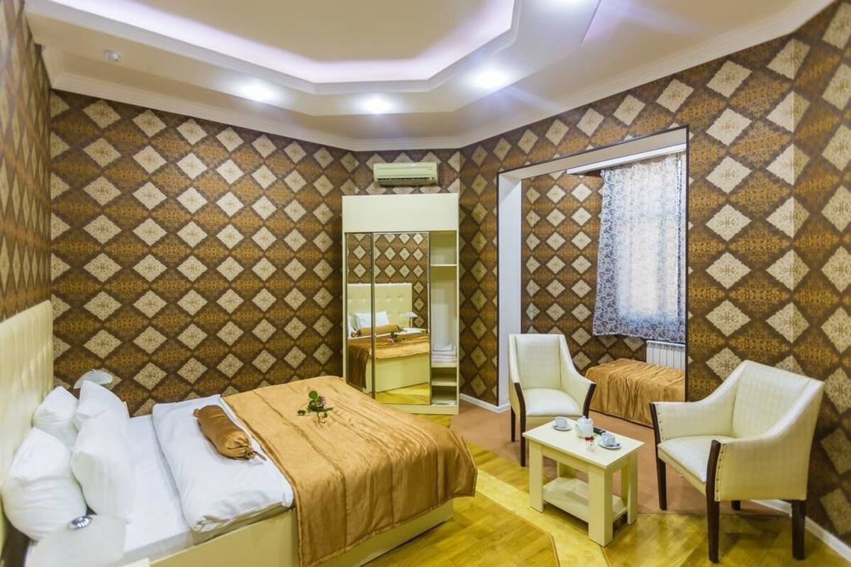 A hotel room with a bed, two chairs, a small table, and a mirror.