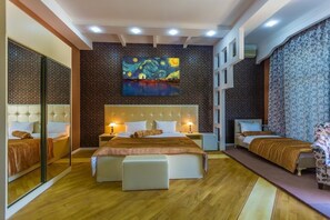 A hotel room with a large bed, a smaller bed, a sofa, a mirror, and a painting on the wall.
