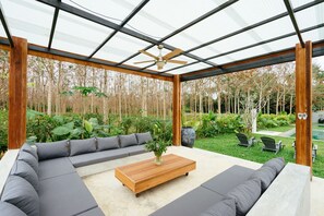 An outdoor patio with a wooden coffee table, grey sofas, and a ceiling fan. - Isara Khao Lak (Takua Pa)