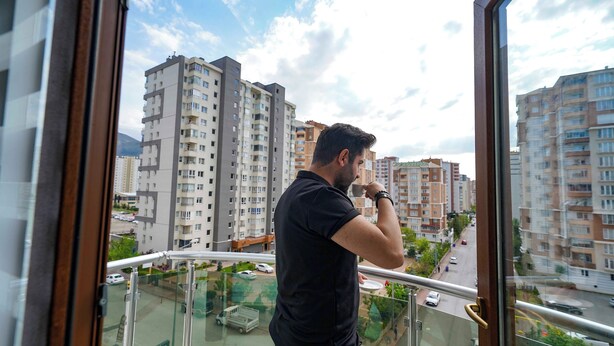 Un homme se tient sur un balcon, d  ’où l’on peut admirer des immeubles résidentiels de grande hauteur.