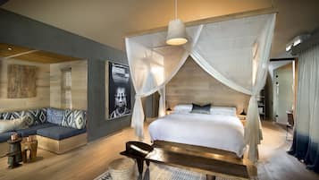 A bedroom with a canopy bed, a sofa, and a rug.