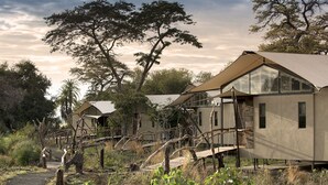 Un lodge de safari doté d’une terrasse en bois et d’une allée couverte.