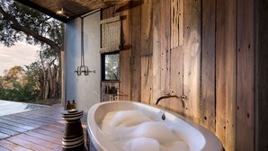 Un espace spa doté d’une grande baignoire à remous, de murs en bois et d’une terrasse en bois.