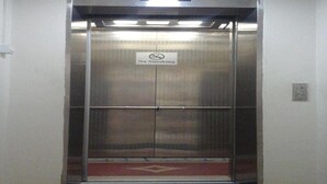 Un ascenseur avec un panneau « Il est interdit de fumer », un paillasson et un luminaire au-dessus.