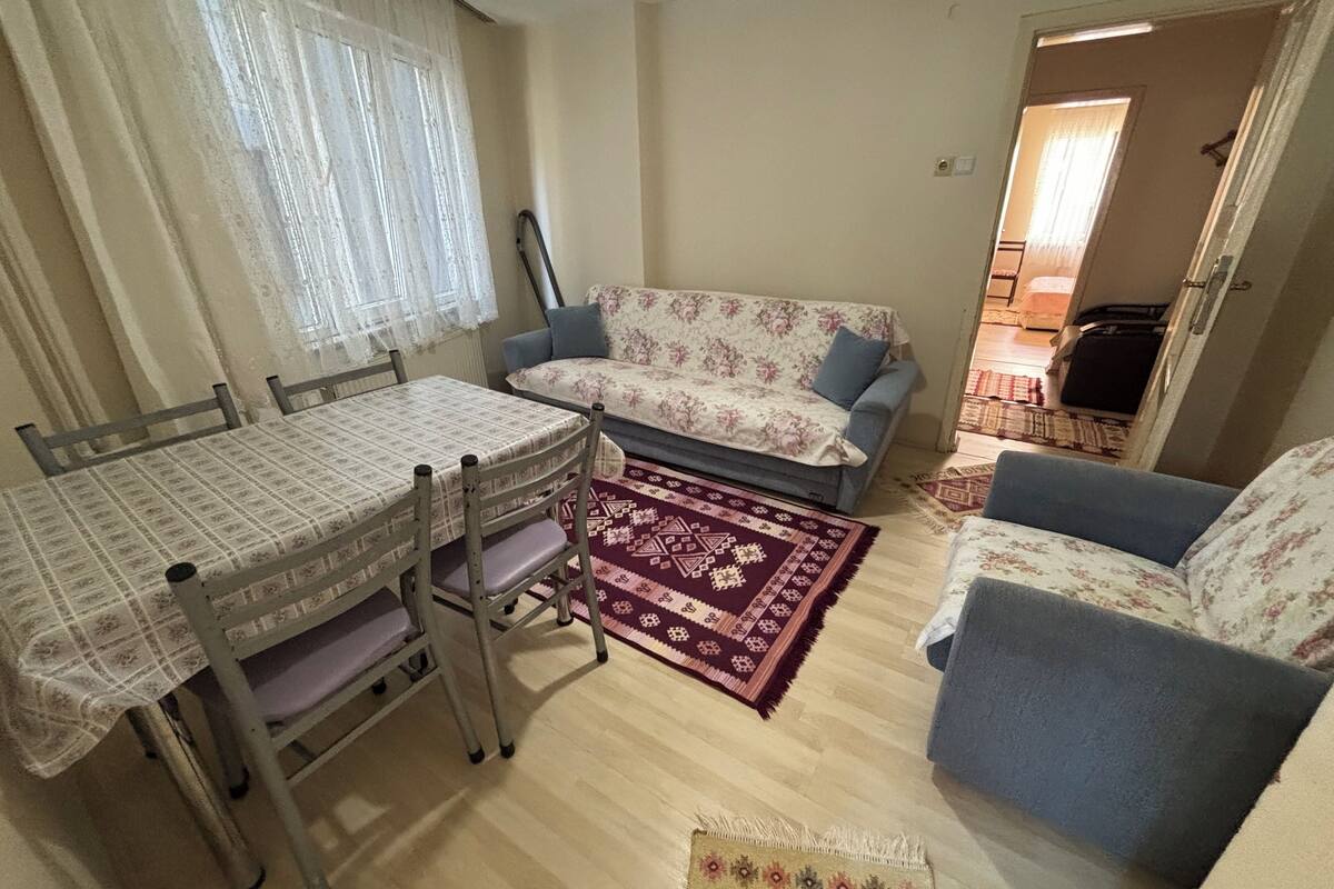 Een woonkamer met een eettafel, twee banken en een kamerbreed tapijt met patroon.