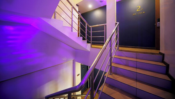 A staircase with a purple-lit wall and a sign indicating room numbers 201-215. - Chimera Hotel (Kota Kinabalu)