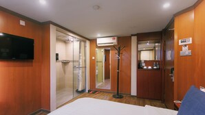 A hotel room with a bed, a TV, a wardrobe, a mirror, and a bathroom visible through a glass door. - Chimera Hotel (Kota Kinabalu)