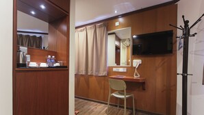 A hotel room with a wooden wardrobe, a desk with a chair, a television, and a coat rack. - Chimera Hotel (Kota Kinabalu)