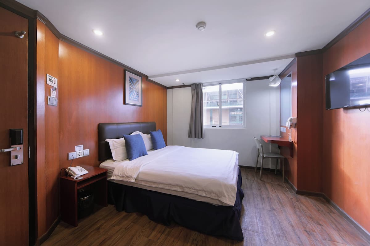 A hotel room with a bed, bedside table, and a desk.