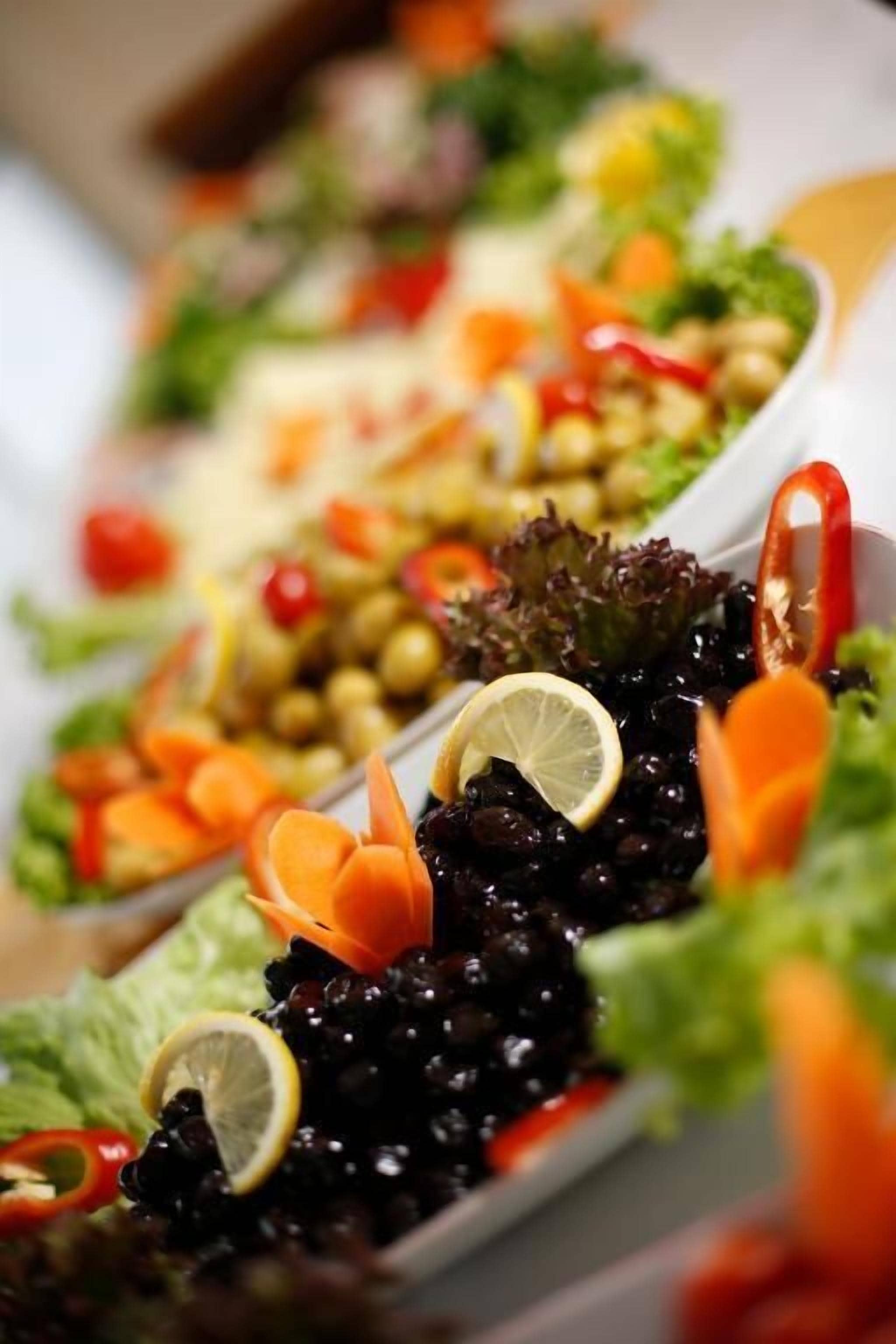 A variety of dishes including black beans, carrots, and a salad with lettuce and red peppers.