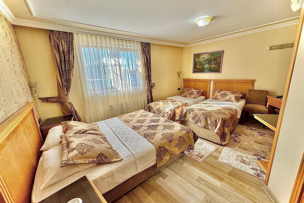 A hotel room with two beds, a desk, and a chair.