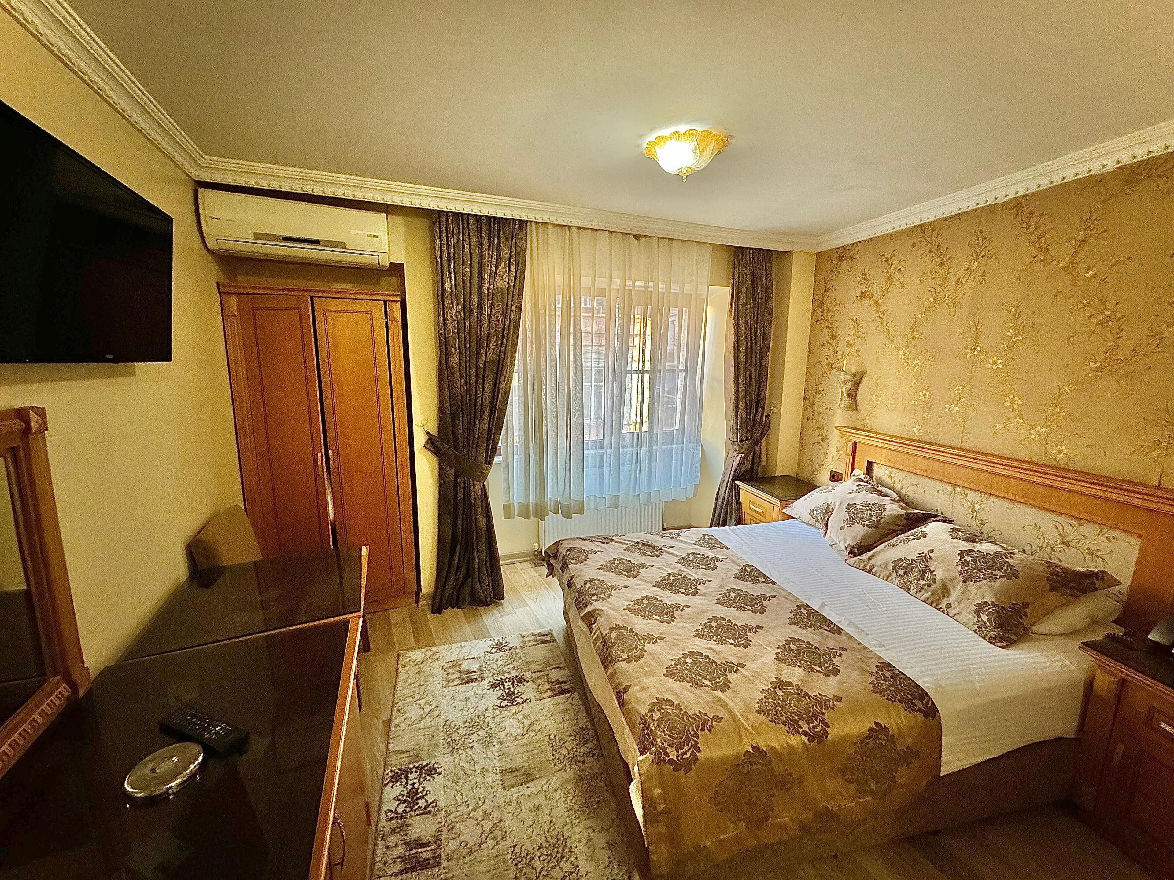 A hotel room with a bed, a TV, a desk, and a wardrobe.