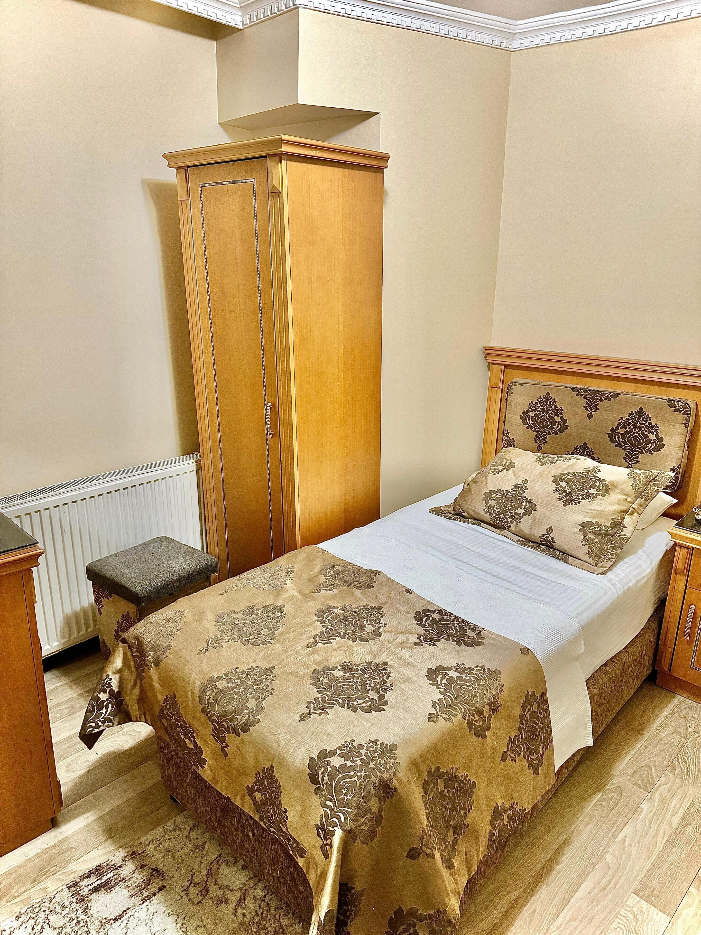 Une chambre à coucher avec un lit, une armoire en bois, une table de chevet et un radiateur.