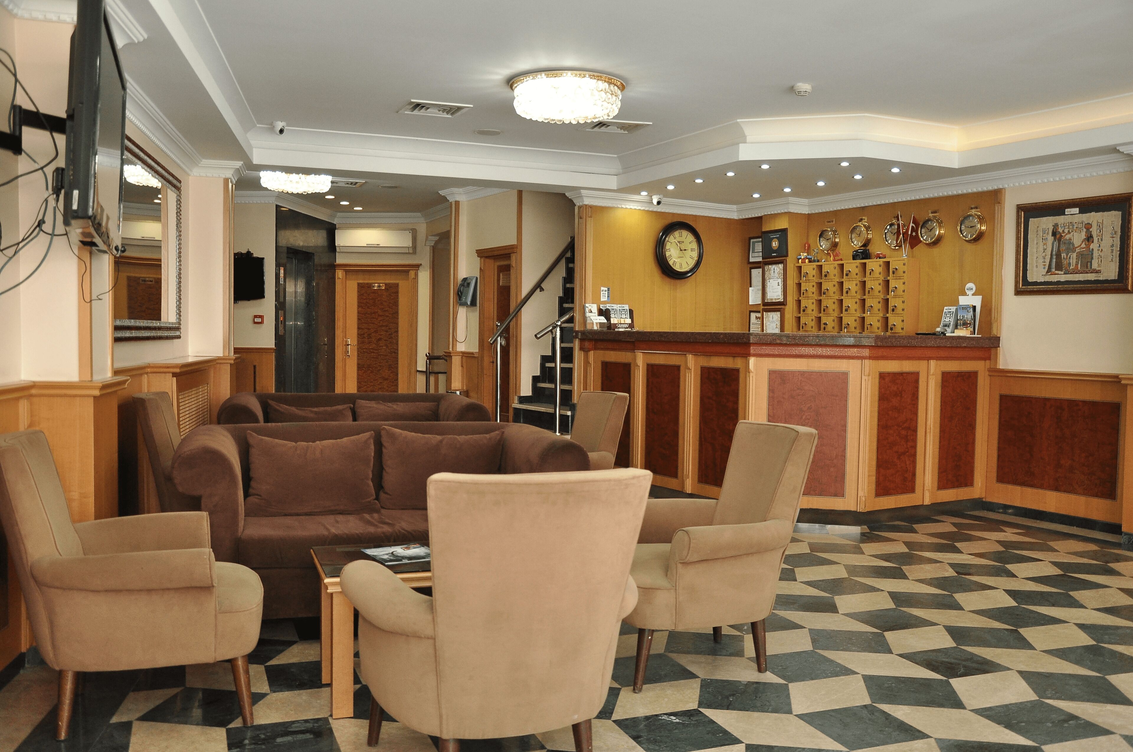 Eine Lobby mit Schachbrettmuster-Boden, einer Rezeption, einer Uhr und einer Treppe.