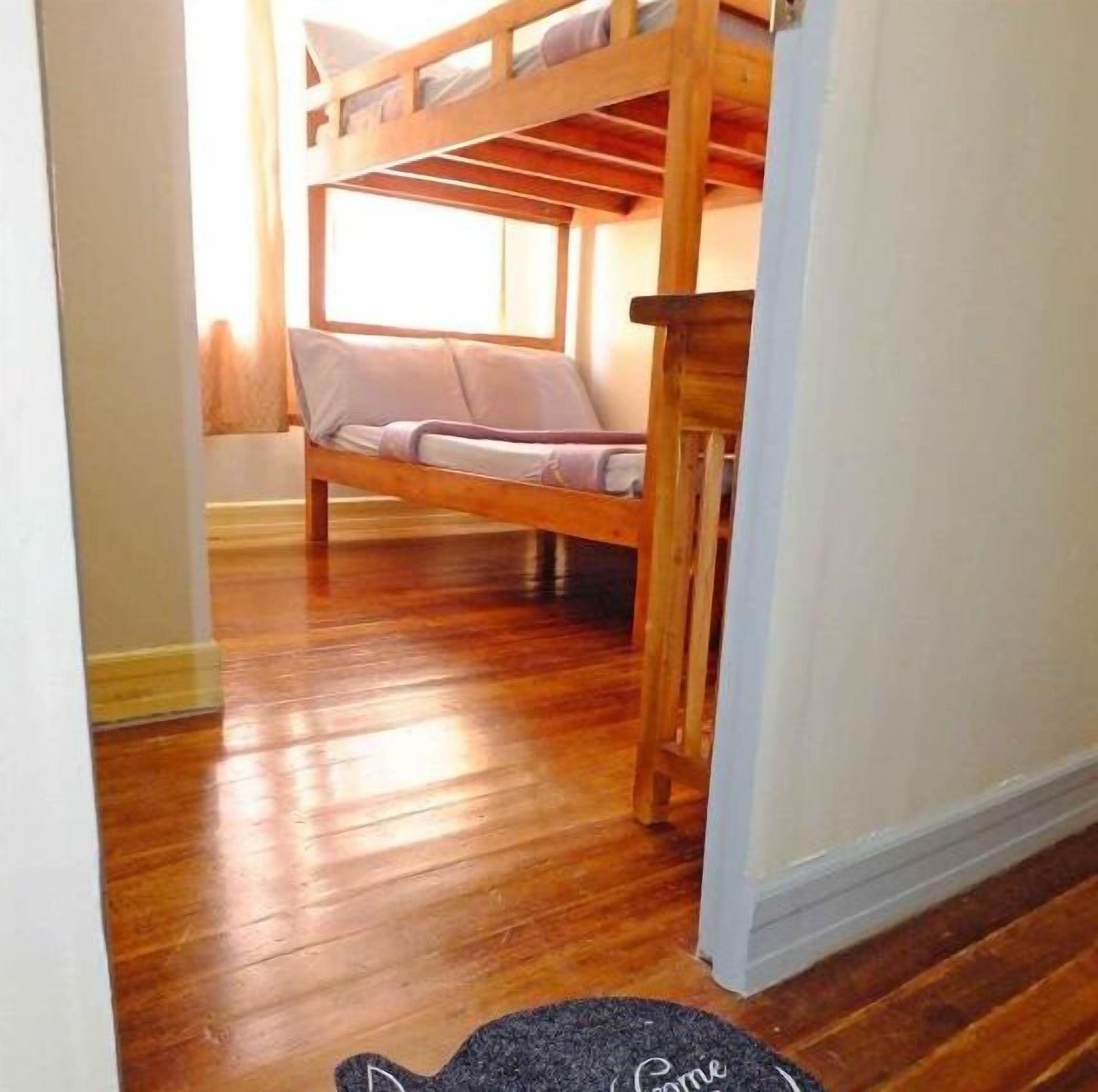Habitación con literas, suelo de madera y ventana que deja entrar luz natural.