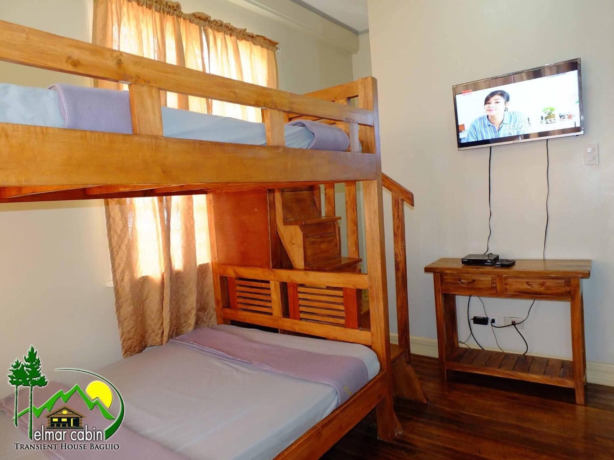 A bunk bed room with a television on a wooden table.