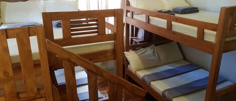 Habitación con literas, barandales de madera y una ventana con cortinas.