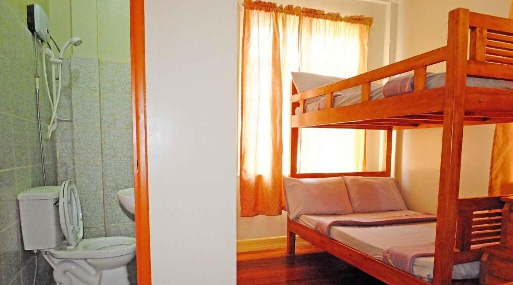 Een badkamer met een douche en toilet, en een kamer met een stapelbed.