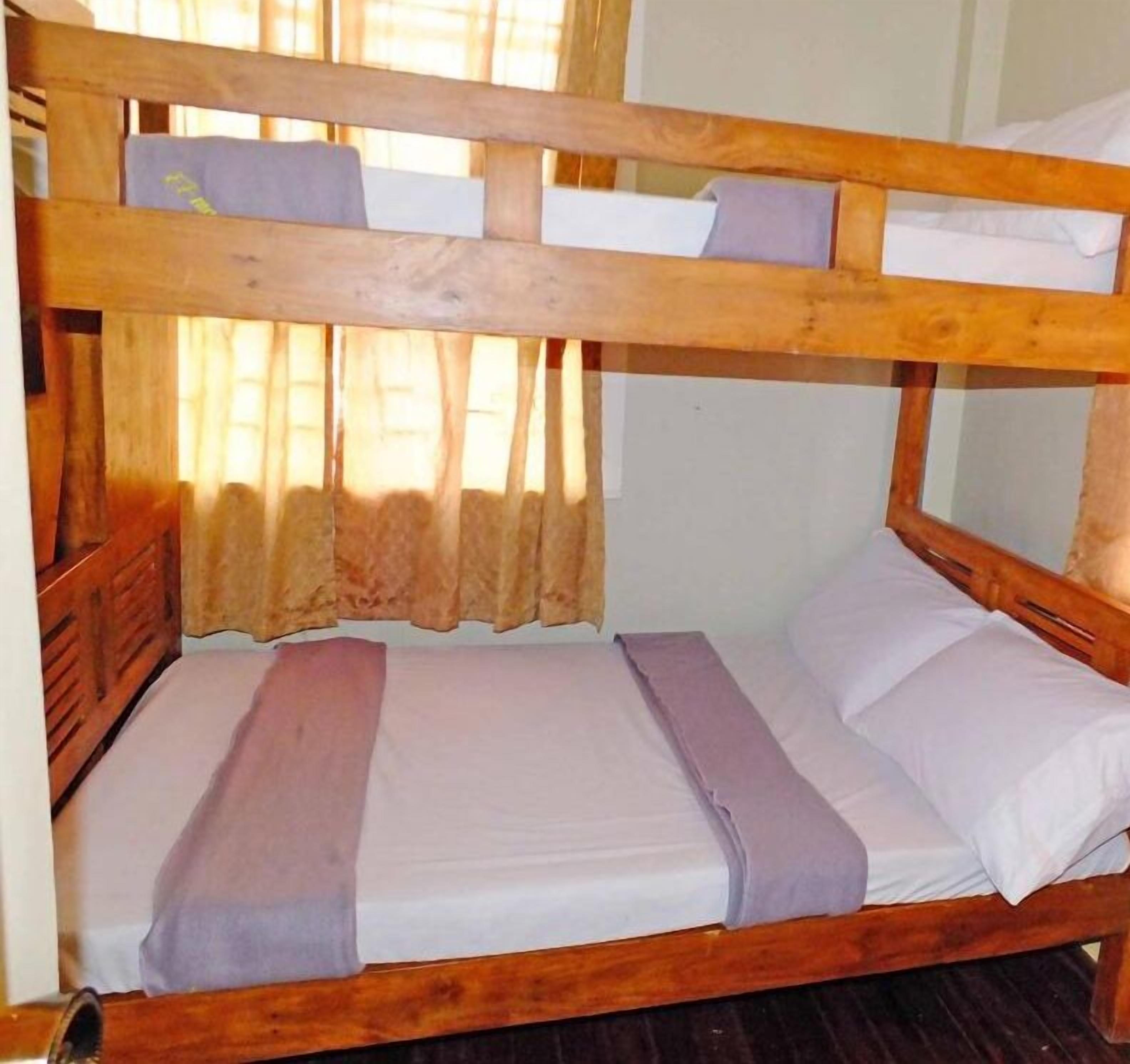 Una cama litera con dos niveles, cada uno con almohada y cobija.