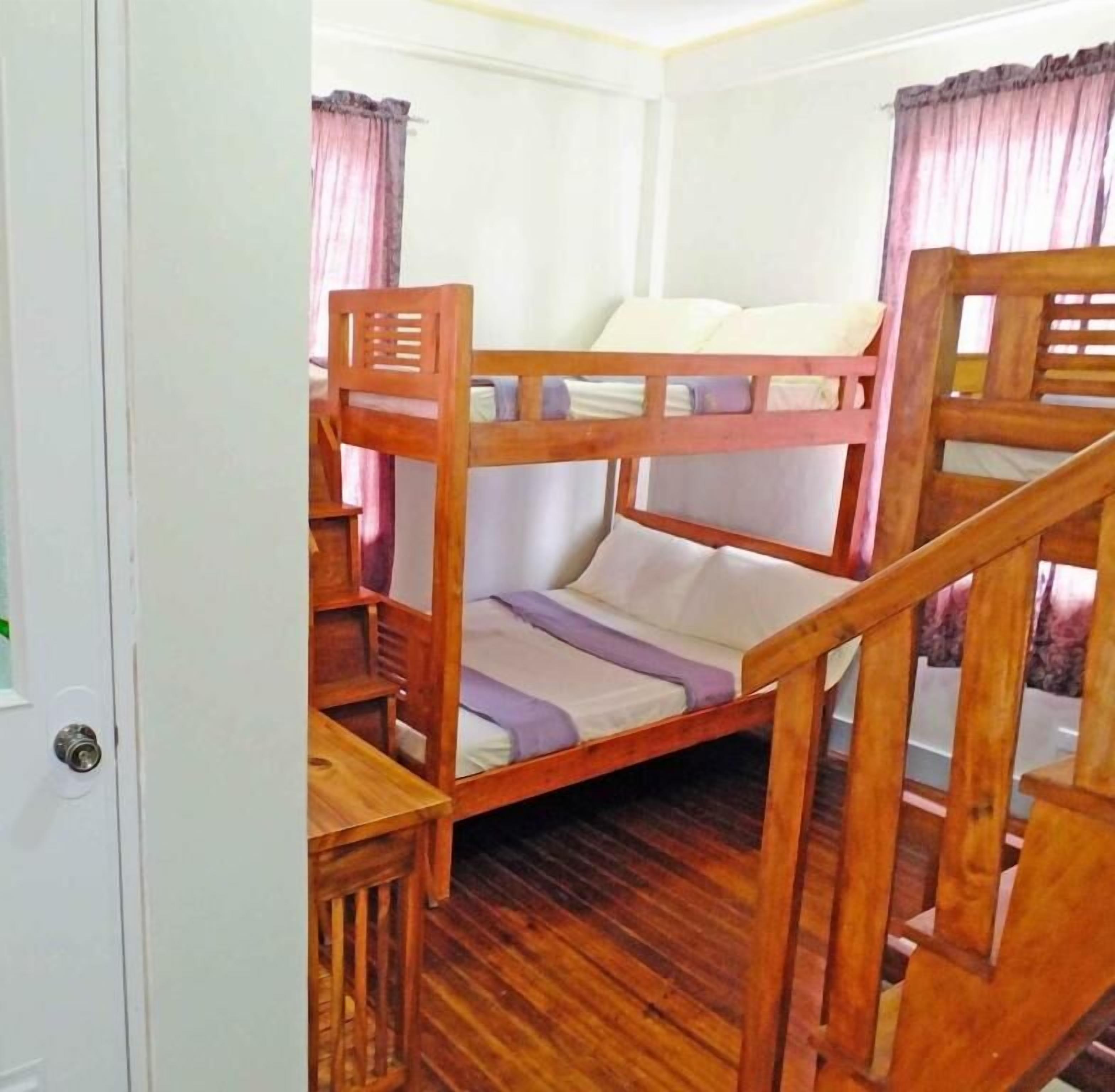 Habitación con literas, escalera de madera y una puerta.