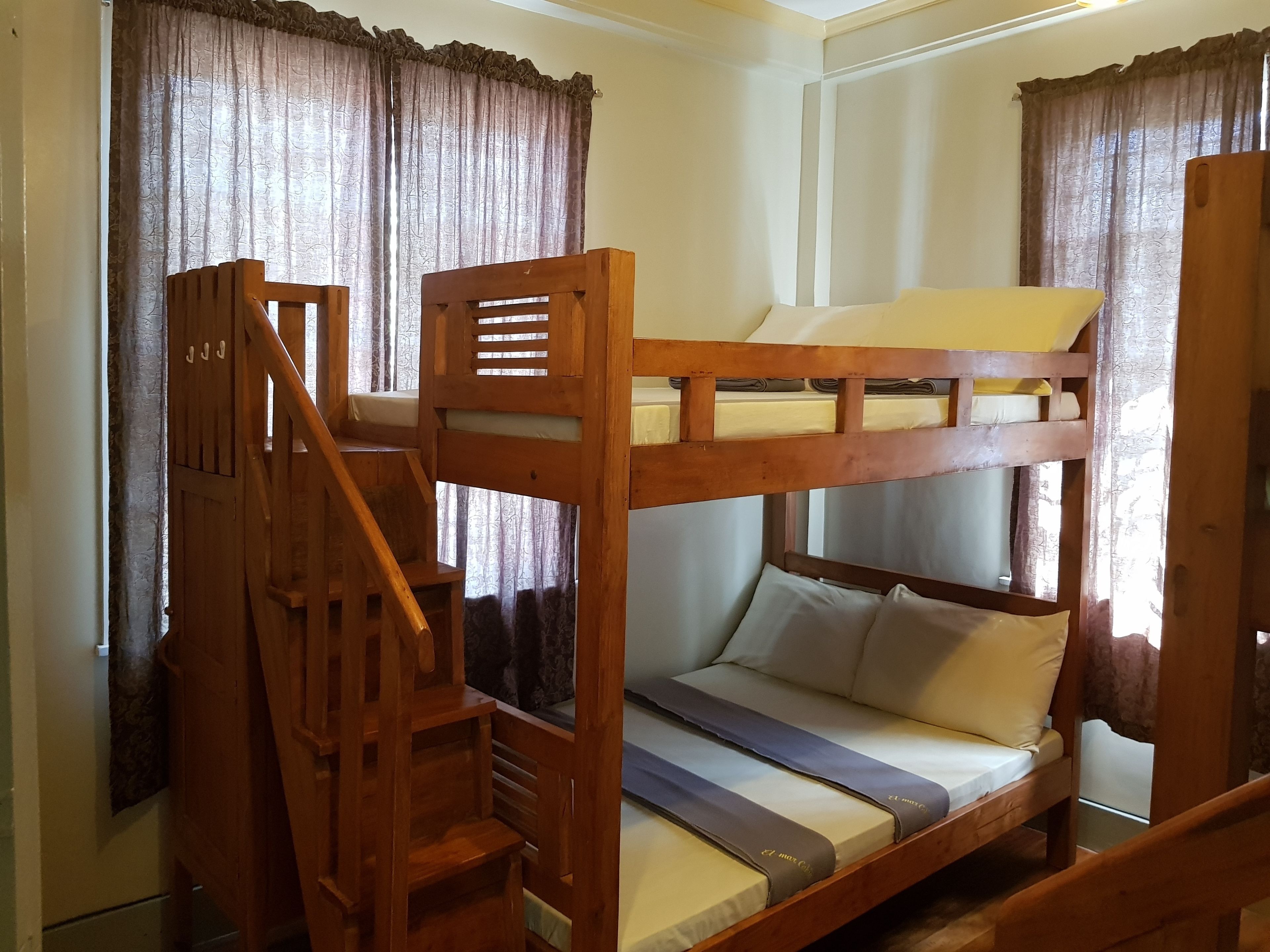 A bunk bed with a wooden ladder and a single bed below.