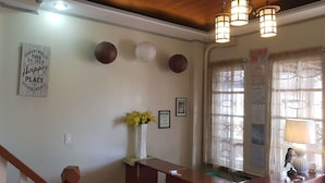 A reception area with a wooden reception desk, a vase of yellow flowers, and a wall with framed certificates and a motivational sign. - Elmar Cabin (Baguio)