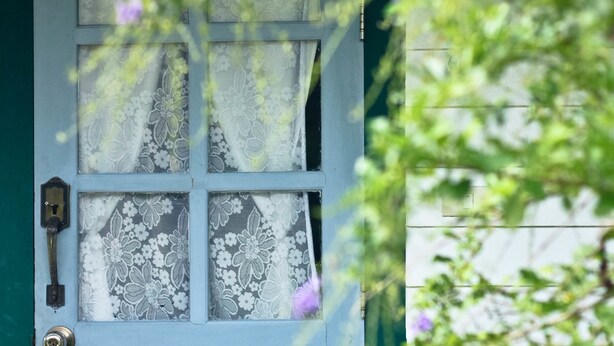 Una porta blava amb una finestra, un cadenat i una clau.