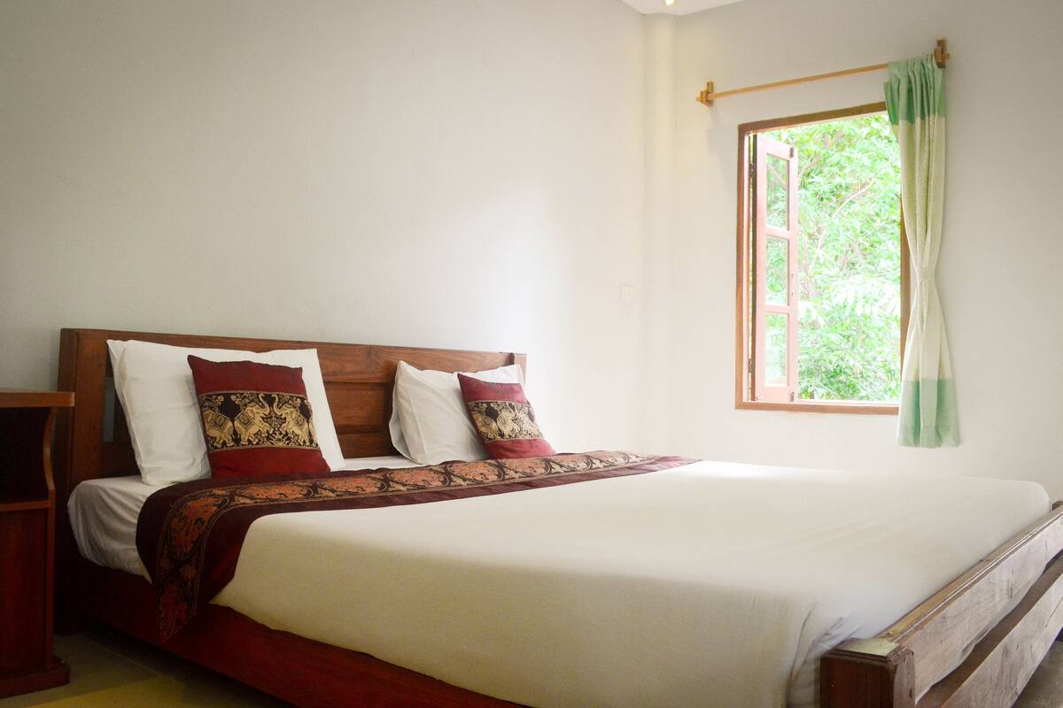 A bed with a wooden headboard, white bedding, and patterned pillows.