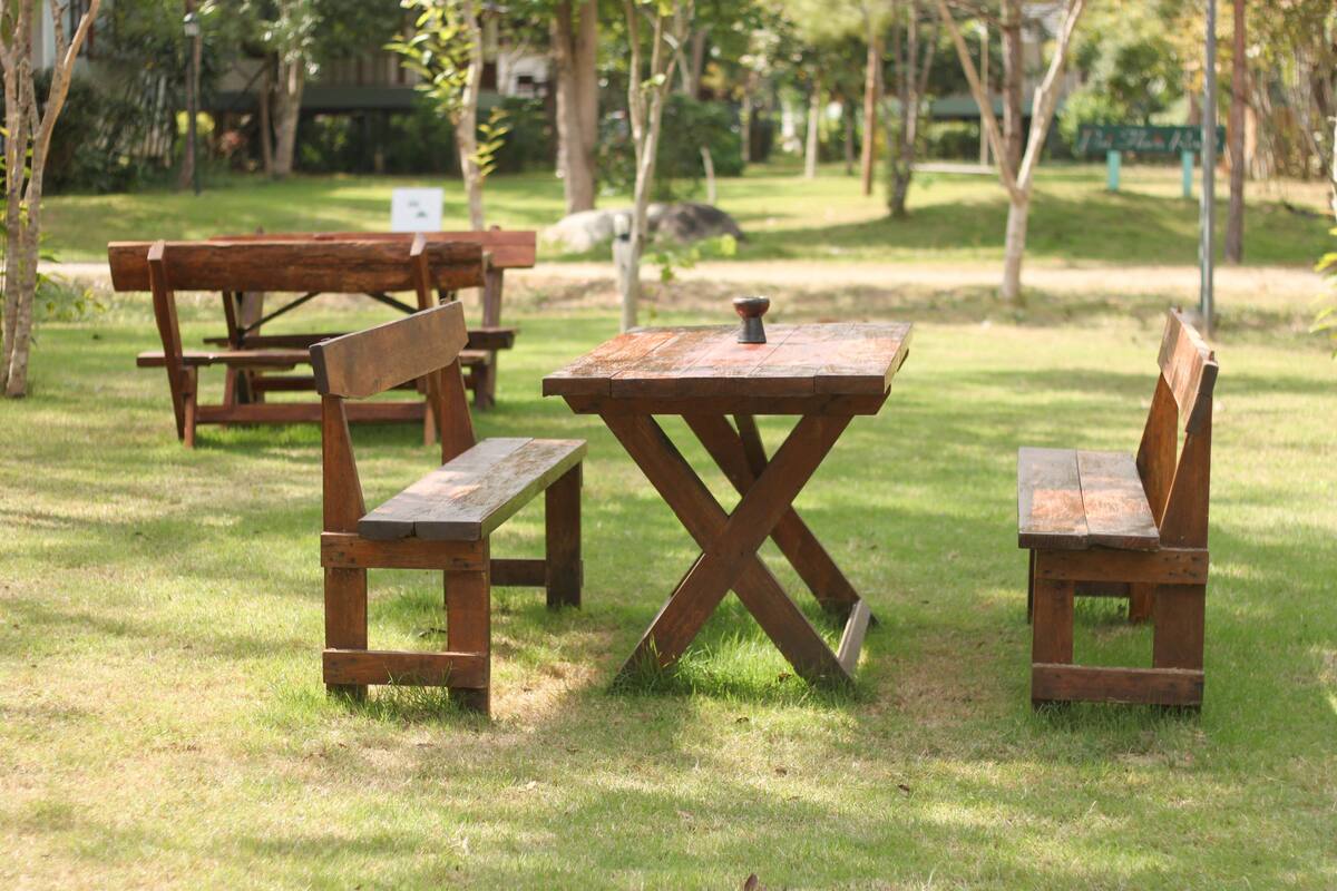 A picnic area with wooden benches and tables in a grassy park.