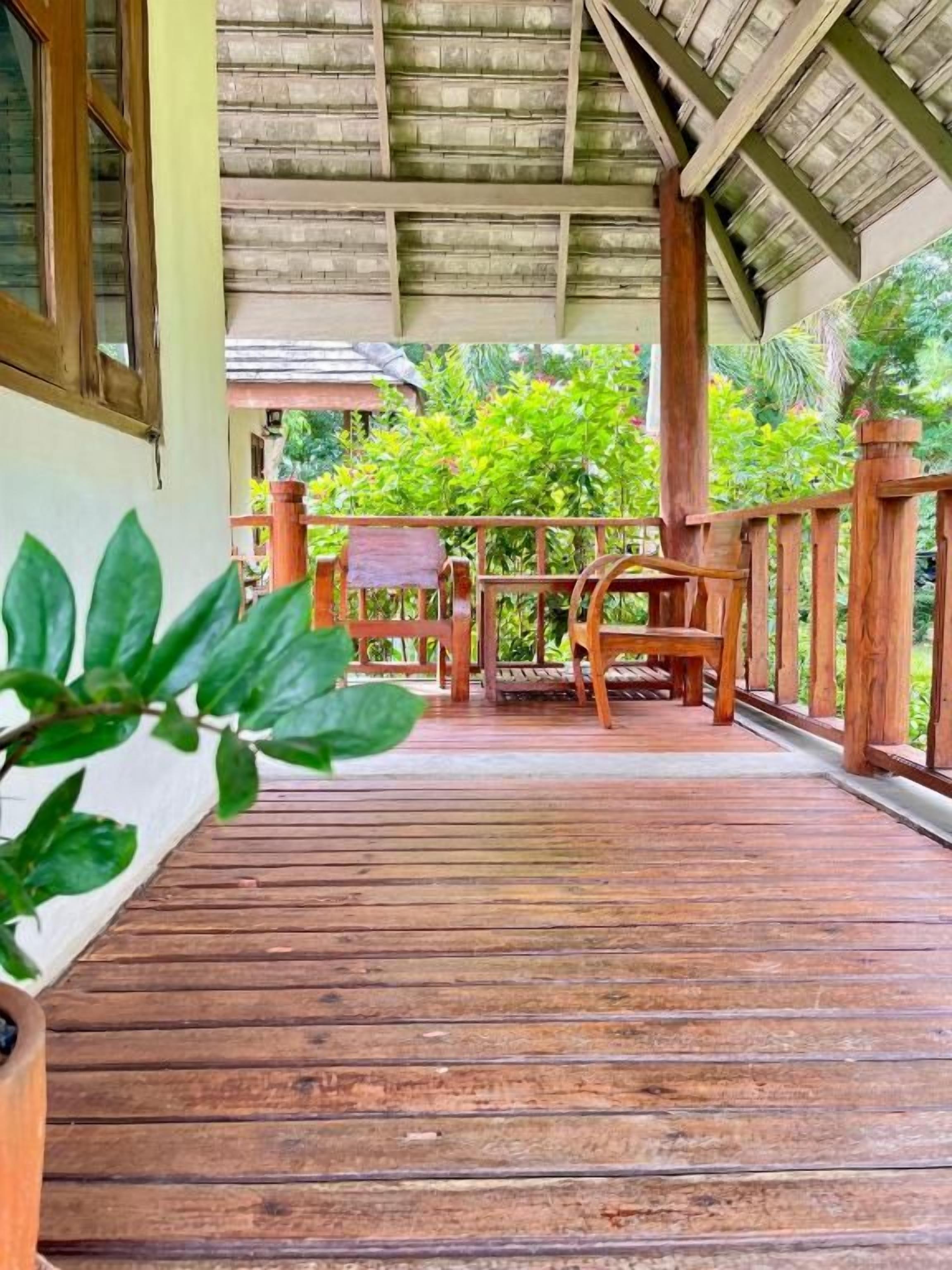 A wooden deck with a railing, a table, and chairs.