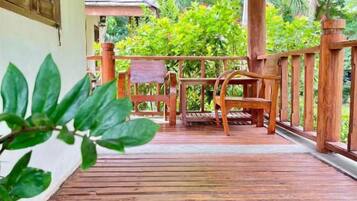 A wooden deck with a railing, a table, and chairs.
