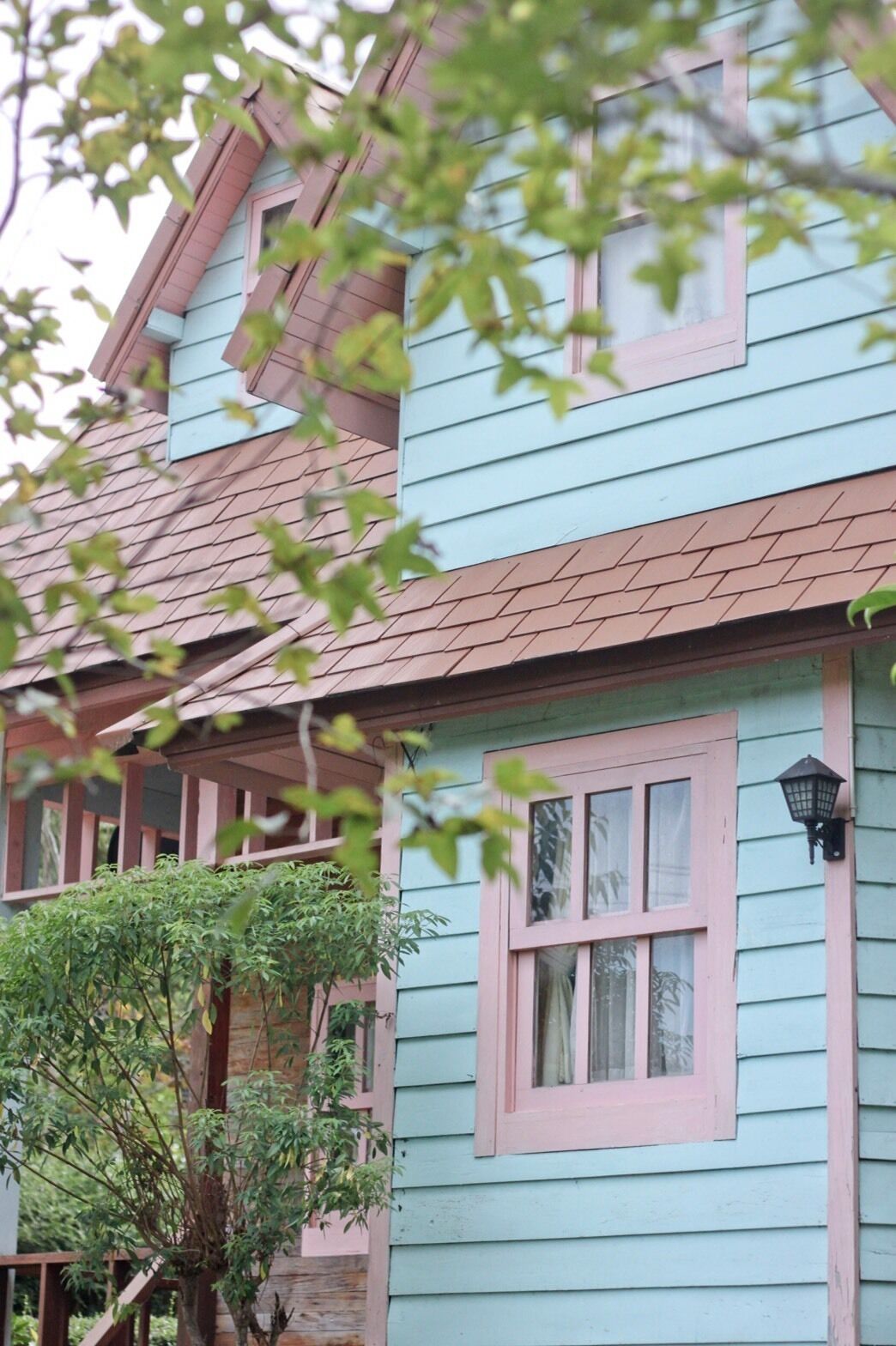 A two-story house with a light blue exterior and a brown roof.