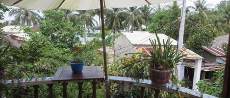 A balcony with a table, chairs, and potted plants.