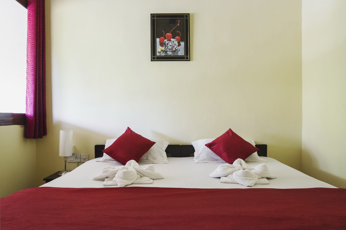 Ein Hotelzimmer mit einem Bett, zwei roten Kissen, einer weißen Decke und einem gerahmten Bild an der Wand.
