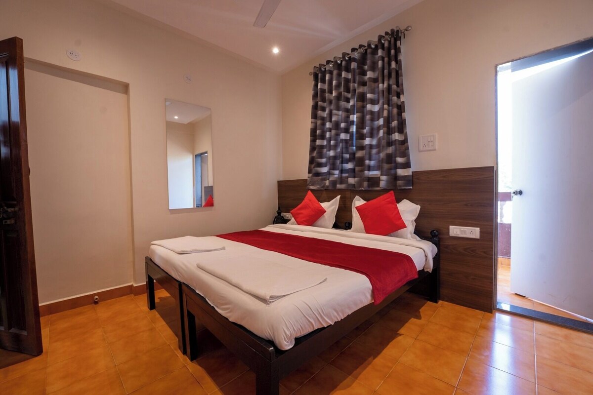 Ein Schlafzimmer mit einem hölzernen Bett, rot-weißer Bettwäsche, einem Spiegel und einem fenster mit Vorhängen.