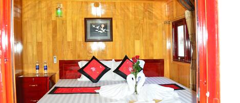 A hotel room with a wooden ceiling, a bed with white linens, red pillows, and a bouquet of roses.