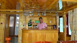 A wooden interior with a reception desk, a chandelier, and a window with curtains. - Ocean Cruise (Hai Phong)
