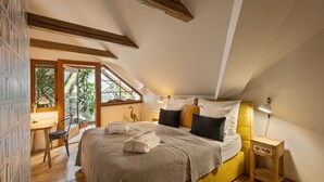 Un dormitorio con una cama grande, un escritorio y una silla. Se ve vegetación a través de la ventana.