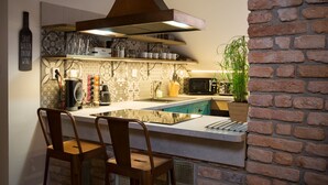 Una cocina con una isla central, taburetes de bar, microondas y una botella de vino colgante con un mensaje.