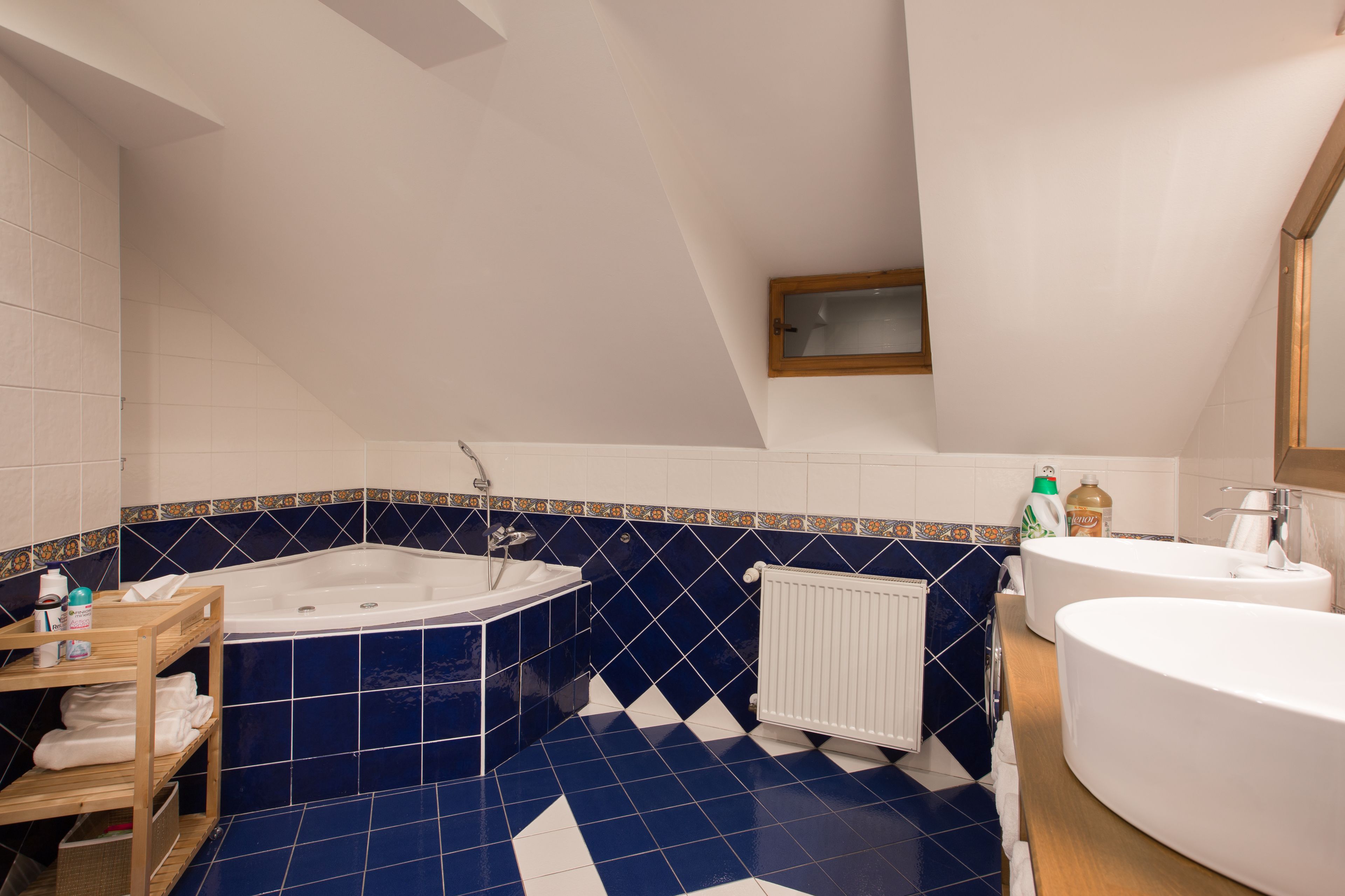 Ein Badezimmer mit einer freistehenden Badewanne, einem Doppelwaschbecken und einem Holzregal mit Handtüchern.