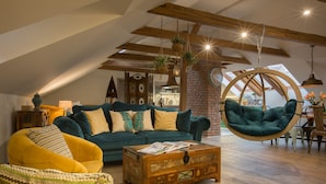 Un salón estilo loft con techo alto, vigas a la vista y una silla colgante.