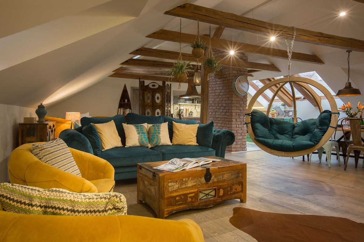 Un salón estilo loft con techo alto, vigas a la vista y una silla colgante.